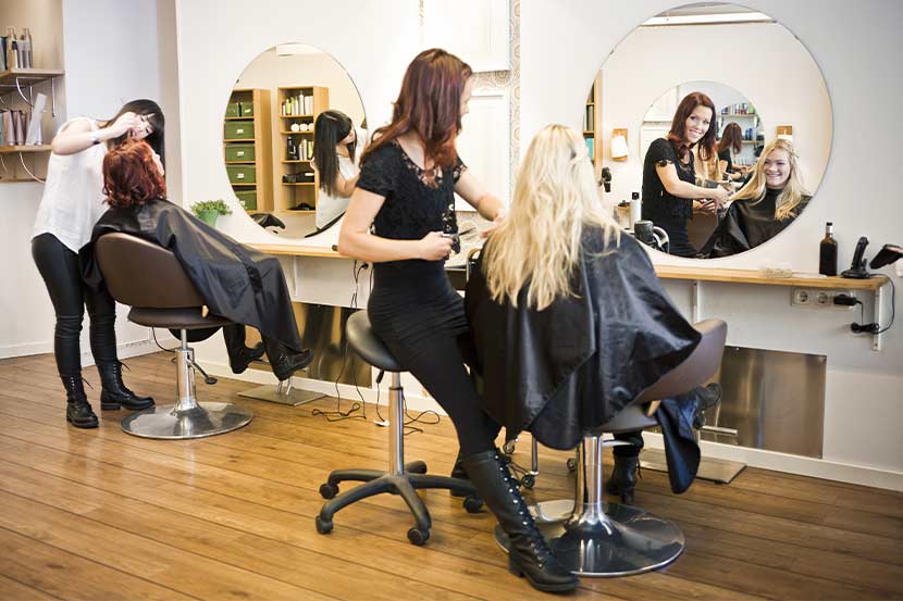 Blonde Kundin beim Friseur Wien im Beauty Salon, wird von einer hübschen brünetten Friseurin bedient.
