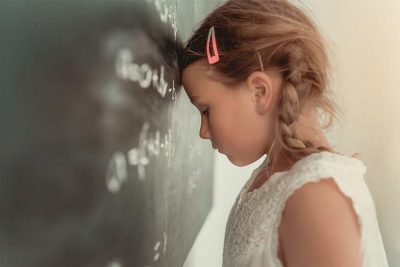 Blondes Mädchen, das aufgrund seiner Legasthenie LRS Rechtschreibschwäche Probleme in der Schule hat.