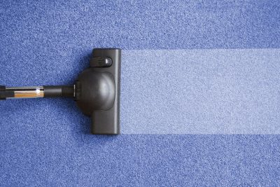 Staubsauger reinigt blauen Teppich
