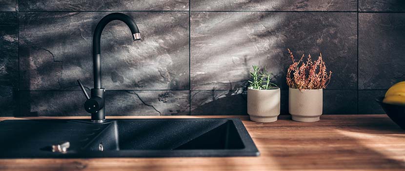 Zementschleier entfernen: Eine moderne Küche mit Natursteinfliesen aus Schiefer und einer Ablagefläche aus rötlichem Holz.