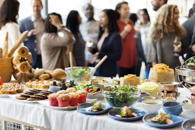 Gruppe von Menschen, die hinter einem Brunch Buffet stehen, das im Vordergrund der Fotografie ist. Brunch Graz.