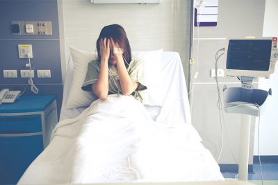 Junge verzweifelte Frau nach Fehlgeburt in einem Krankenhausbett.