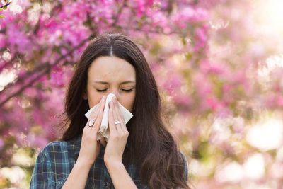 Frau putzt sich die Nase wegen Pollenallergie