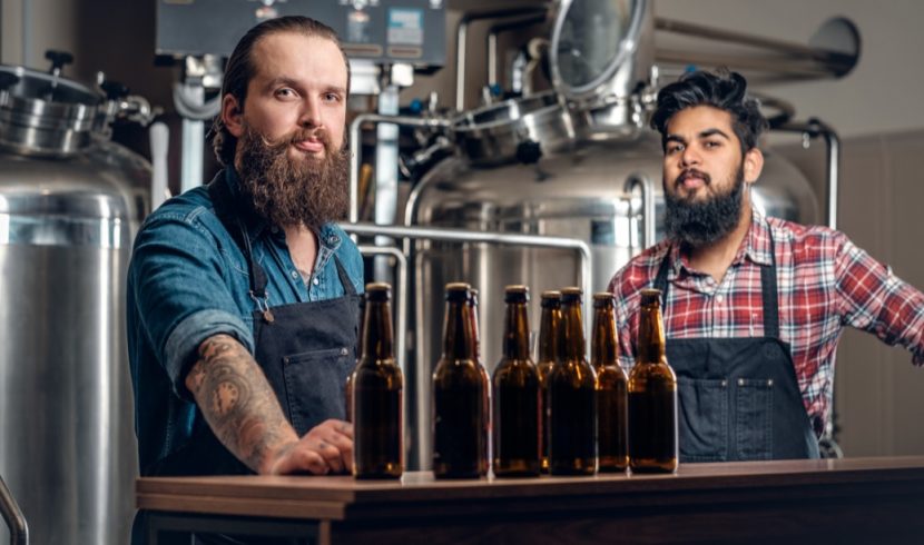 Zwei junge, gutaussehende Braumeister, die in einer Craft Beer Brauerei verschiedene Sorten präsentieren. Craft Beer Wien.