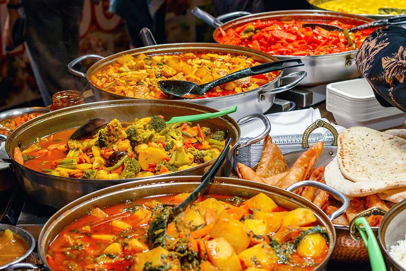 Indische Restaurants Wien: Ein Tisch voller bunter indischer Gerichte wie Curry, Naan und Samosas.
