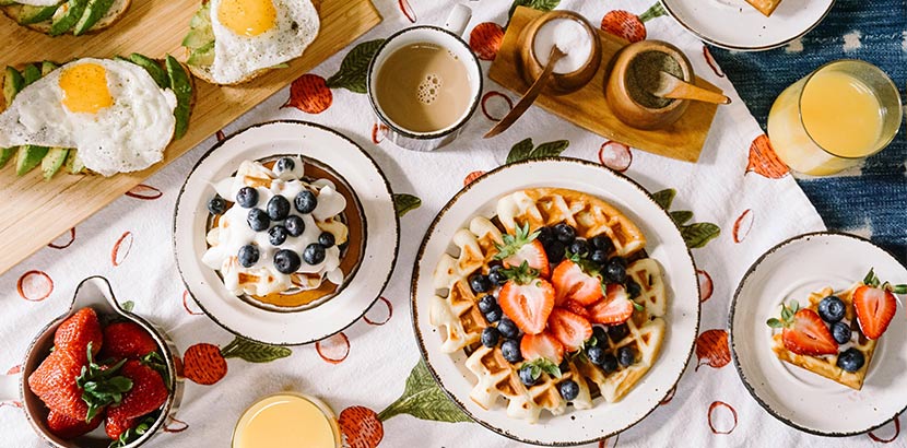 Frühstück Salzburg: Ein Frühstückstisch mit Pancakes, Waffeln, Spiegeleiern, Kaffee und frischen Früchten