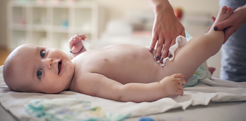 Ein Baby in Rückenlage dessen Windel gewechselt wird.