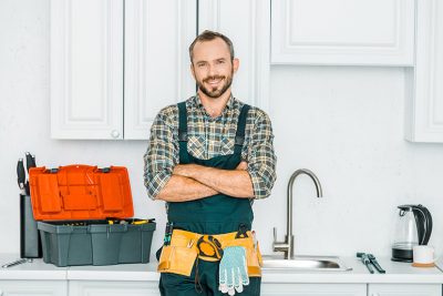 Gutaussehender Installateur mit Werkzeuggürtel in einer Küche. Installateur Wien.