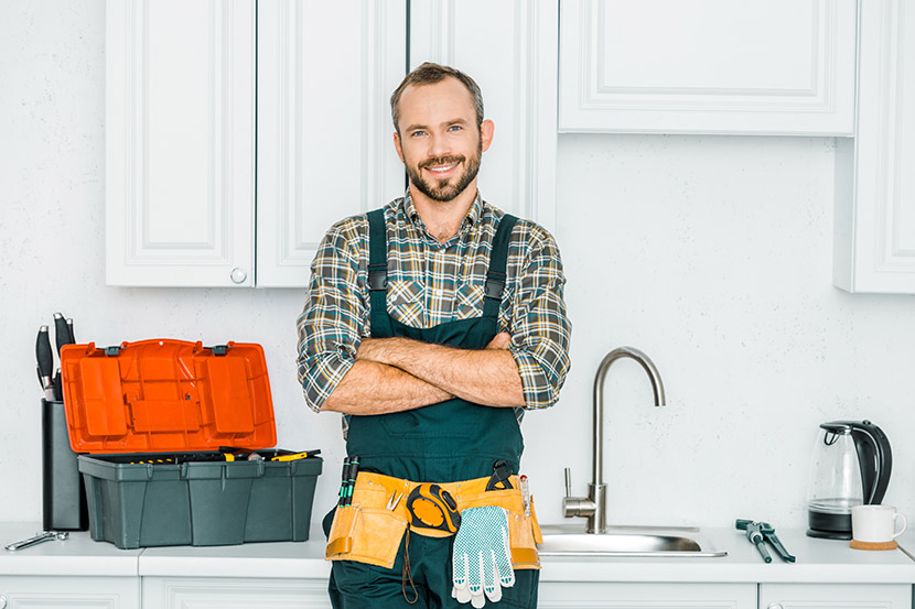 Gutaussehender Installateur mit Werkzeuggürtel in einer Küche. Installateur Wien.