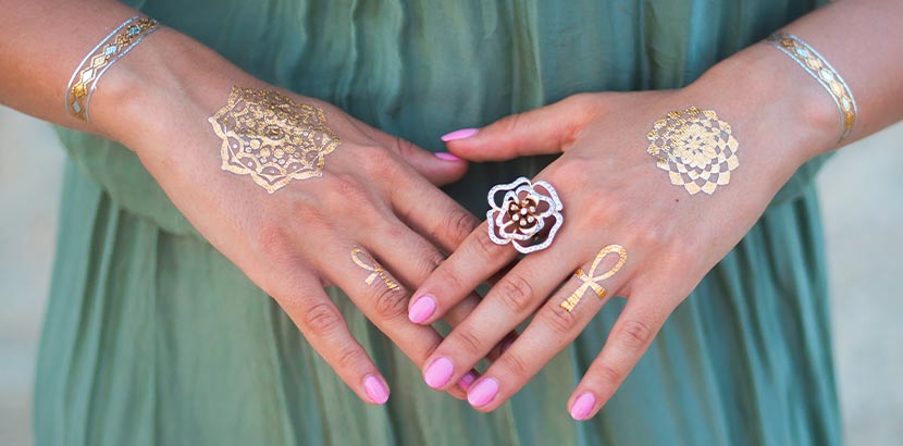 Festival-Pacliste: eine Frau mit goldenen Henna-Tattoos und rosa Fingernägeln