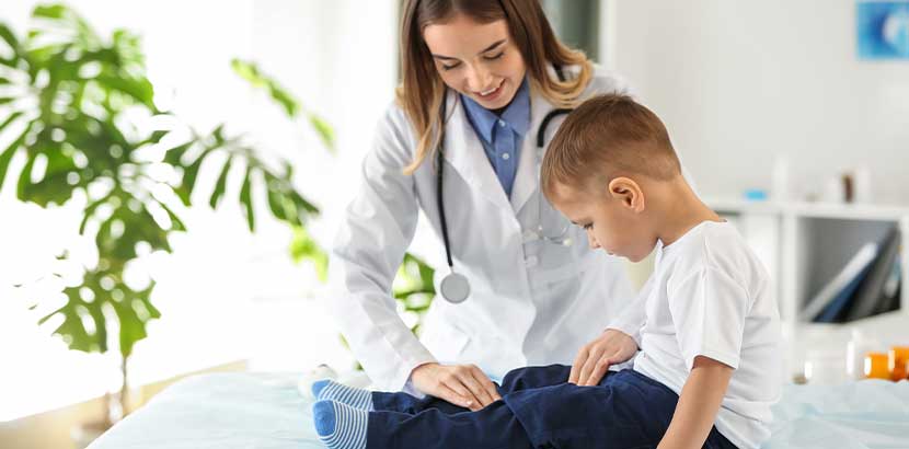 Fachärztin für Kinderorthopädie, die einen Dreijährigen auf Fußfehlstellungen untersucht.