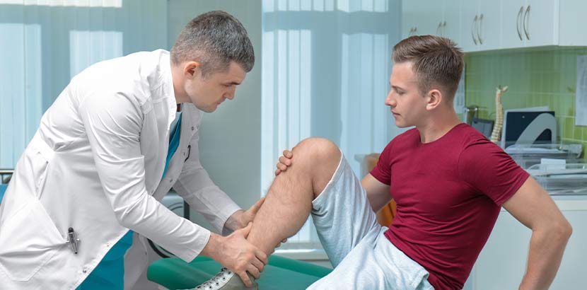 Stoßwellentherapie Wien: Ein Orthopäde untersucht das Knie eines Patienten.