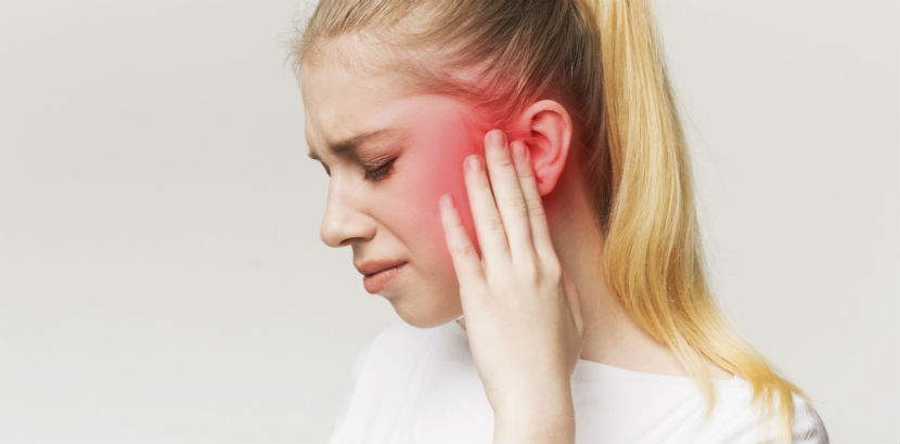 Eine junge Frau leidet unter Tinnitus.