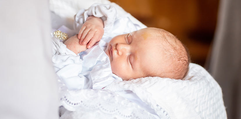 Katholische Taufe vorbereiten: Ein Baby in weißem Taufkleid