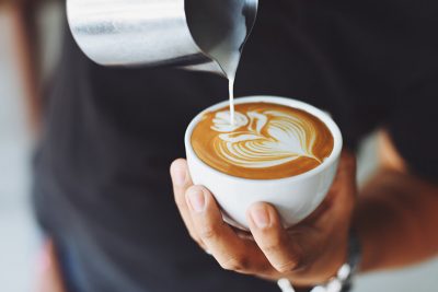 Kaffeehaus Linz: Eine Person bereitet einen Milchkaffee zu