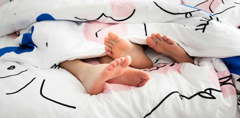 Geschlechtskrankheiten testen Wien: Vier Füße schauen unter einer Bettdecke hervor.