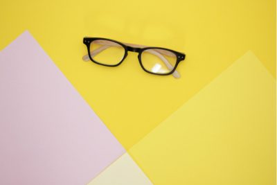 Optiker Wien: Brille vor gelbem Hintergrund.