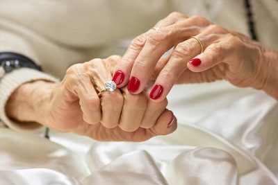 Alte Frau mit schön manikürten Fingern, die einen Diamantring an ihrem Finger berührt. Diamantbestattung Österreich.
