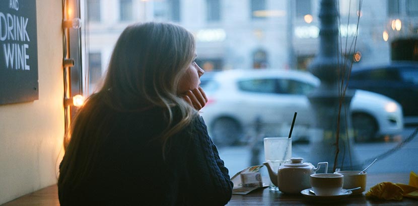 Ängstliche junge Frau sitzt alleine und einsam in einem Cafe.