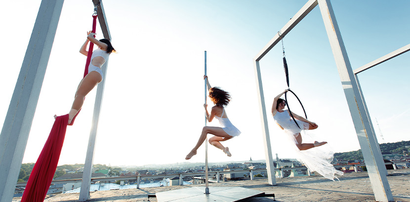 Aerial Silk Wien, Aerial Hoop Wien, Aerial Poledance Wien: Drei Frauen üben an Tüchern, Stange und Reifen Aerial Fitness Übungen aus