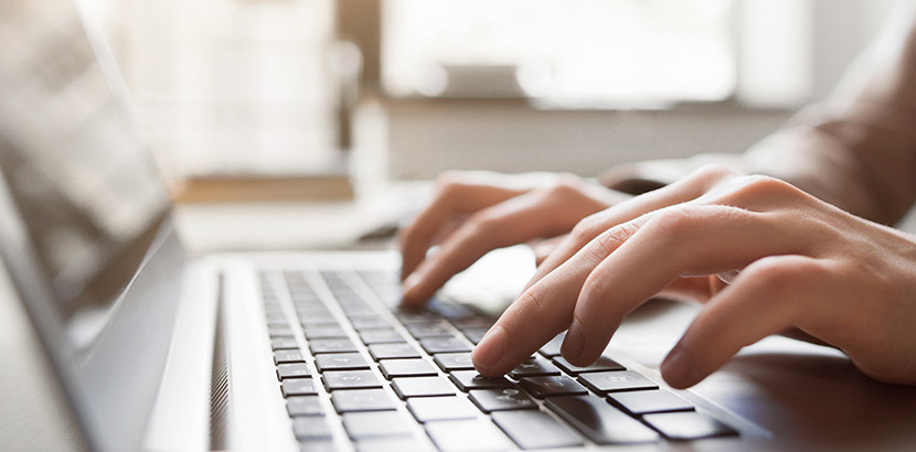 Die Tastatur eines Laptops, auf der zwei Hände etwas tippen.