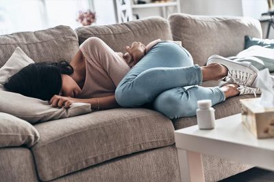 Prämenstruelles Syndrom (PMS) Frau mit Schmerzen auf Sofa