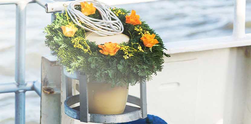 Seeurne mit Blumenschmuck bei Seebestattung an Bord eines Schiffes.