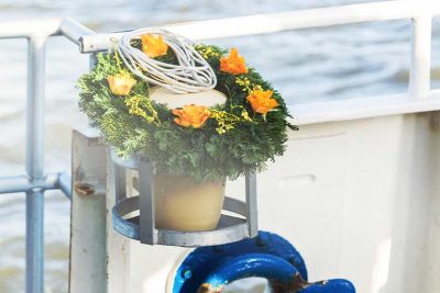 Seeurne mit Blumenschmuck bei Seebestattung an Bord eines Schiffes.