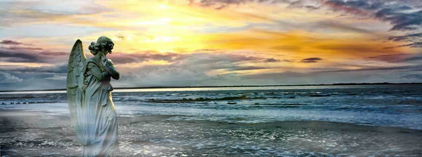 Steinerner Engel am Strand bei Sonnenuntergang. Seebestattung Österreich.