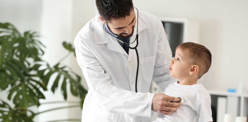 Junger Arzt, der das Herz eines kleinen Jungen abhört. Kinderkardiologe Wien.