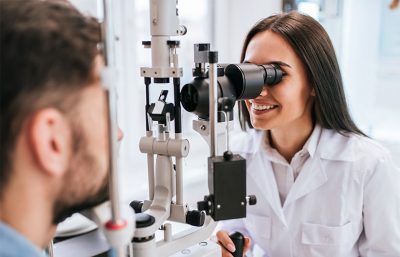 Eine Augenärztin, die durch ein Gerät hindurch in das Auge eines Patienten schaut.