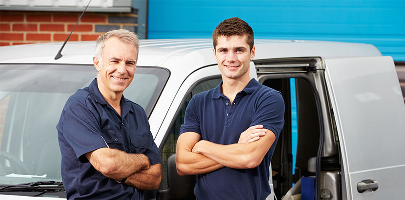 Vater und Sohn, die gemeinsam als Handwerker arbeiten, stehen vor einem Lieferwagen. Schenkungsvertrag.