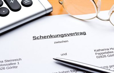 Eine Nahaufnahme von einem Schenkungsvertrag, auf dem ein Kugelschreiber liegt.