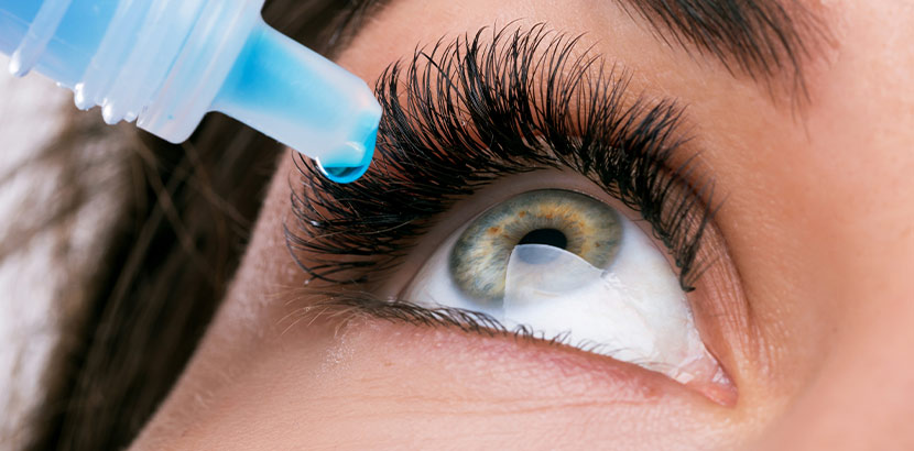 Eine Nahaufnahme von einem Auge, in das aus einer Flasche Augentropfen eingetropft werden.