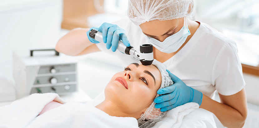Hübsche junge Hautärztin, die eine dermatologische Untersuchung bei einer jungen brünetten Patientin macht. Hautarzt Graz.