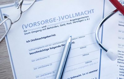 Gedruckte Formulare mit Logo auf der eine Brille, ein Kugelschreiber und ein Stethoskop liegen.