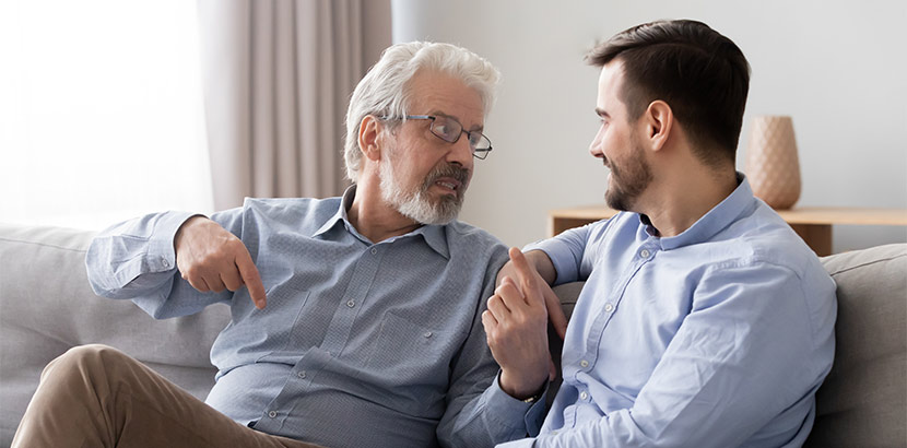 Ein Vater und Sohn, die auf dem Sofa sitzen und miteinander reden.