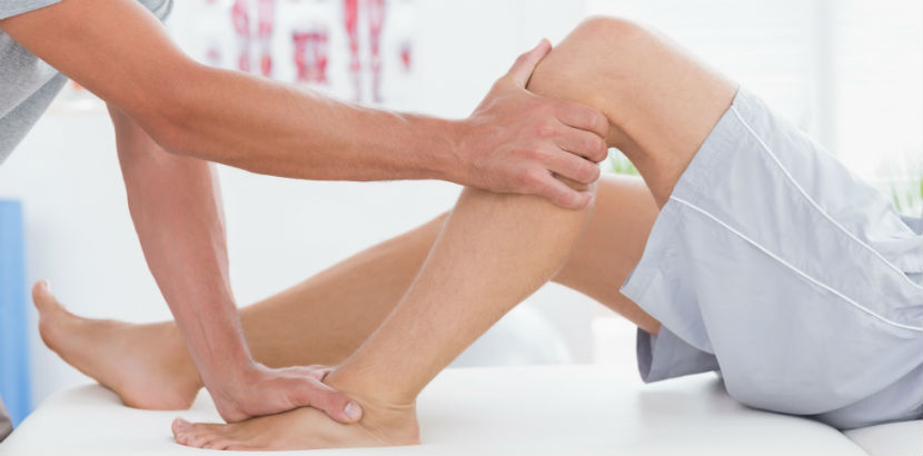 Physiotherapie Graz: ein Therapeut winkelt das linke Bein eines Patienten ab