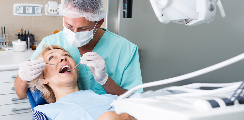 Ein Zahnmediziner untersucht eine Patientin, die auf dem Zahnarztstuhl sitzt.