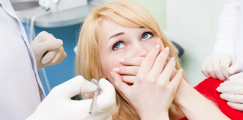 Eine Frau mit Zahnarztangst legt ihre Hände über den Mund.
