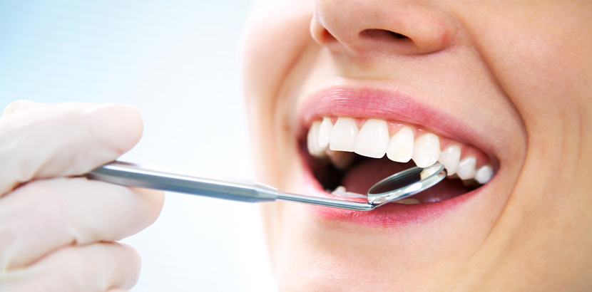 Eine Frau mit strahlend weißen Zähnen wird beim Arzt untersucht.