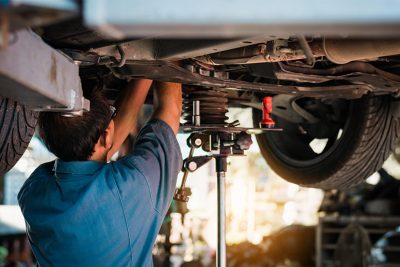 Automechaniker repariert Unterboden eines Autos in einer Autowerkstatt in Salzburg