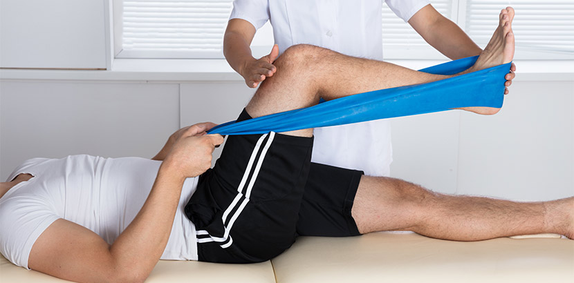 Ein Physiotherapeut dehnt die Muskeln eines betroffenen Patienten.