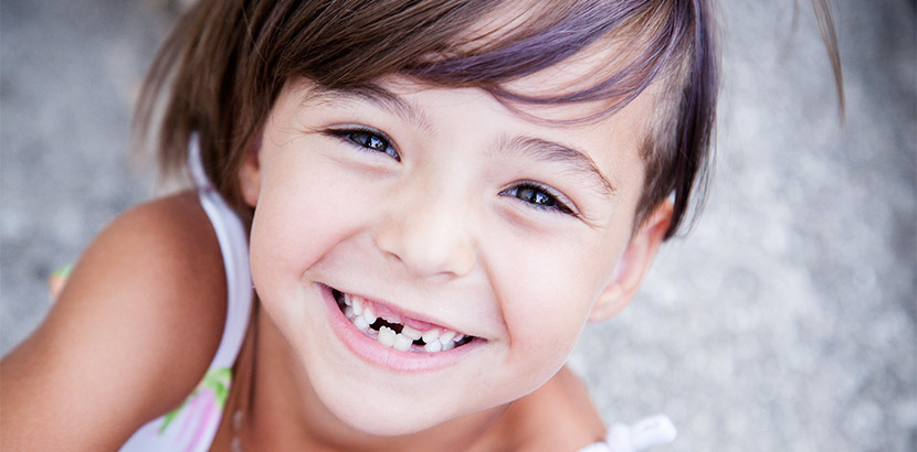Ein junges Mädchen lächelt mit Zahnlücken im Milchgebiss.