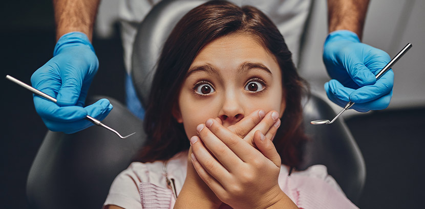 Ein Mädchen hält beim Zahnarzt ihre Hände über den Mund.