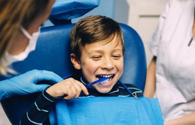 Ein Junge der beim Kinderzahnarzt Zähneputzen lernt.