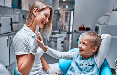 Ein junges Mädchen gibt ihrer Kinderzahnärztin ein High Five.