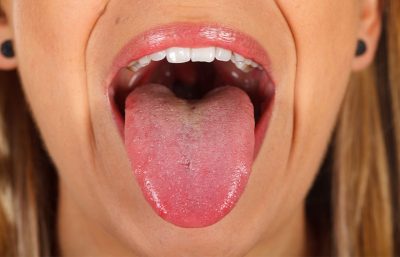 Frau streckt nach dem Essen ihre gesunde Zunge aus dem Mund. Hausmittel