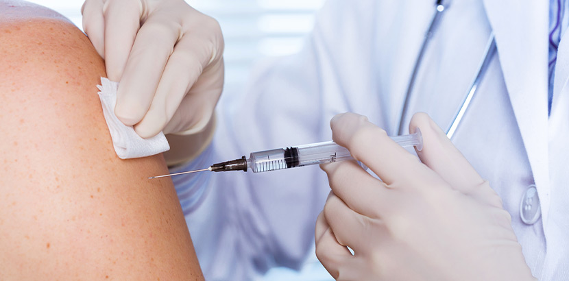 Ein Arzt, der eine Spritze mit einer Impfung am Arm des Patienten ansetzt.