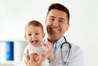 Ein Arzt hält ein Baby auf dem Arm.